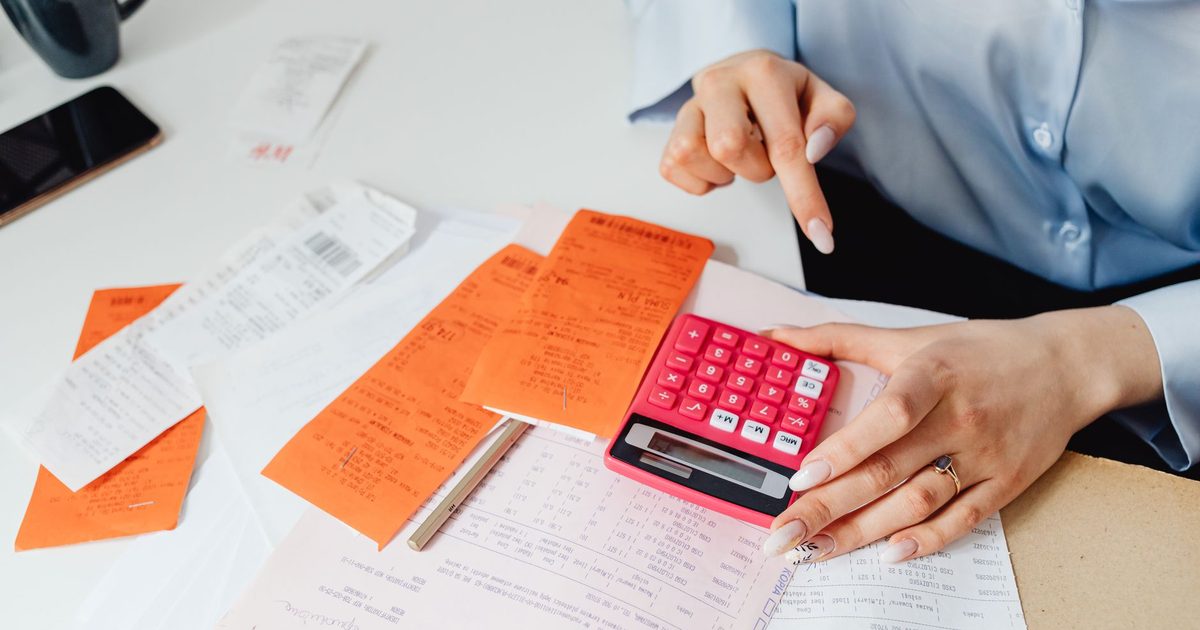 Manos con calculadora, recibos y cuentas escritas a mano sobre la mesa
