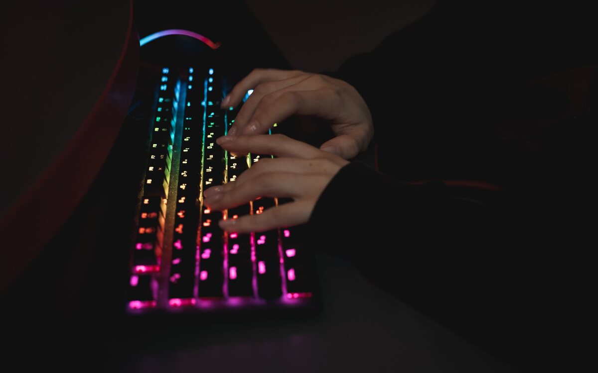 Hands typing on a keyboard on a dark desk