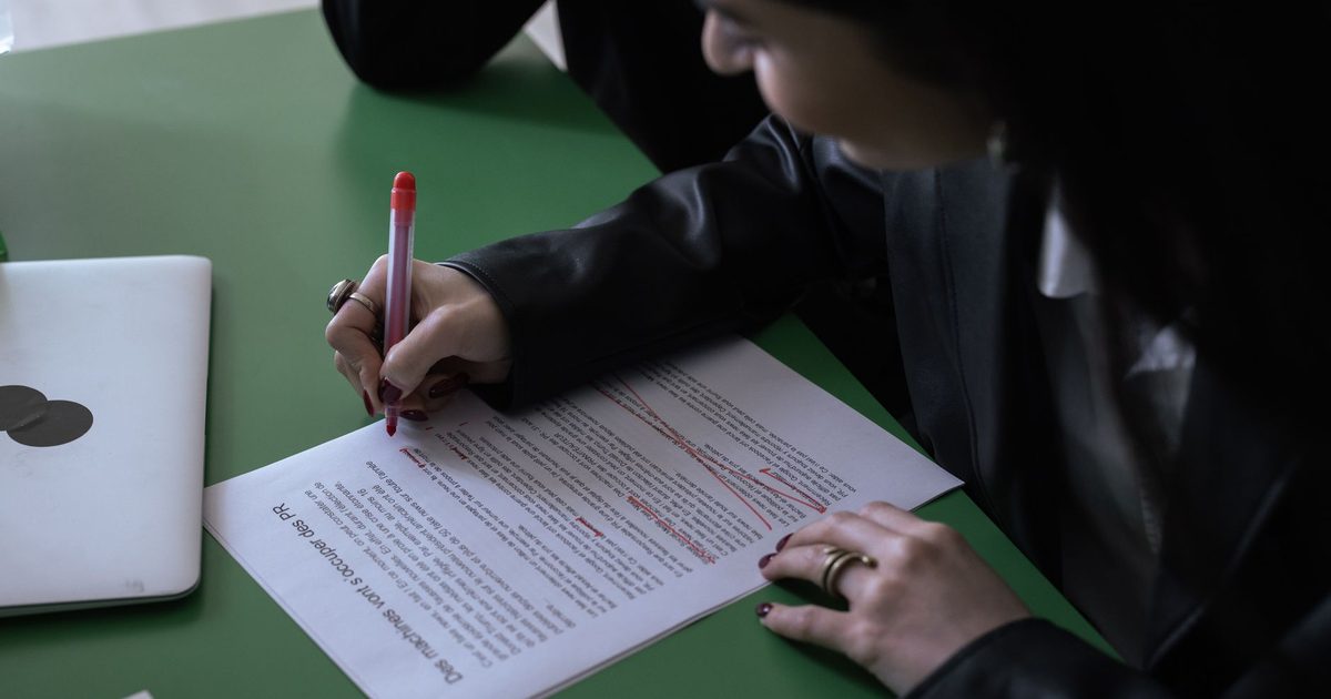 Persona corrigiendo un documento impreso con bolígrafo rojo