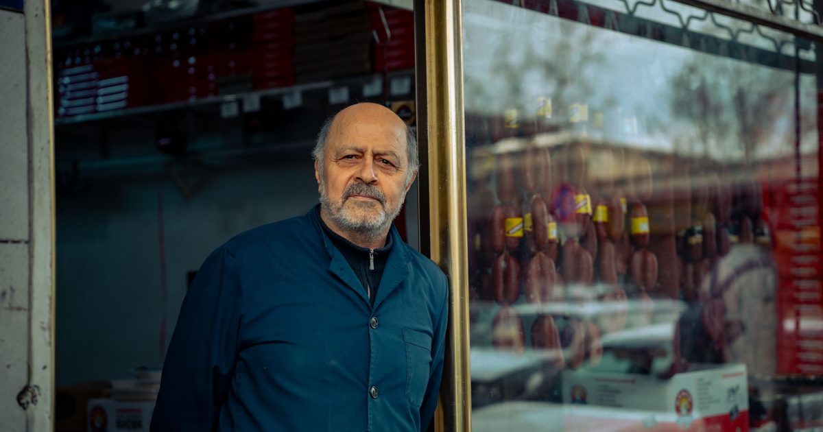 Comerciante mayor de pie en la puerta de su propia tienda